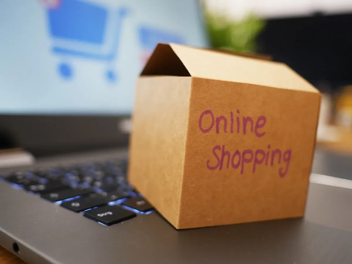 Osoba robiąca zakupy online na ekranie laptopa, symbolizująca wygodne zamawianie produktów przez internet.